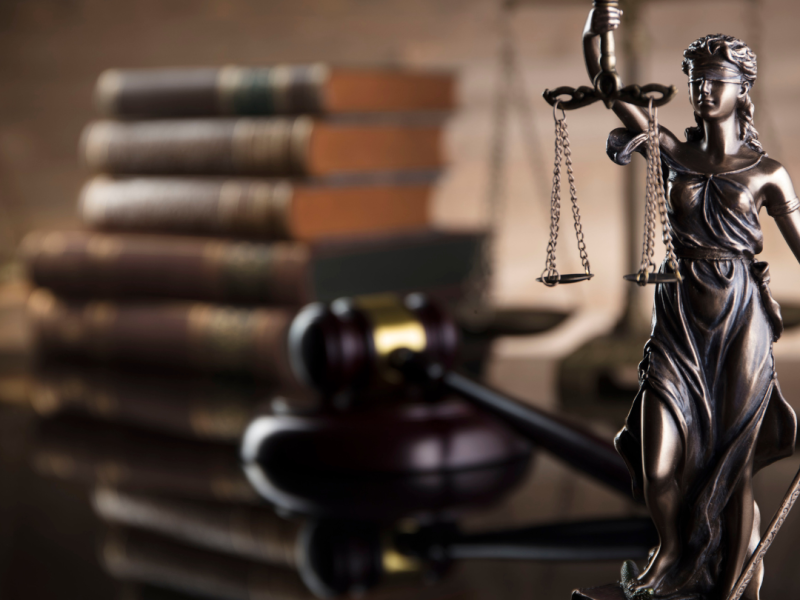 lady justice statue in the foreground with a gavel and books in the background