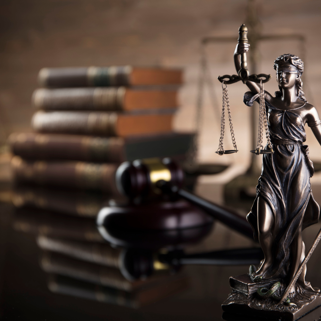 lady justice statue in the foreground with a gavel and books in the background